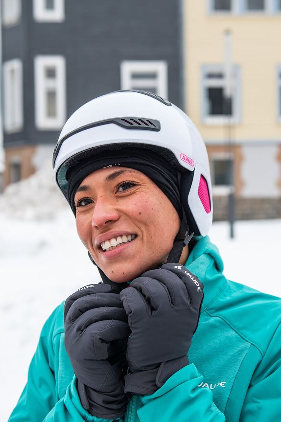 Eine dünne Mütze wärmt im Winter unter dem Helm. Frau mit Fahrradhelm im Winter mit Schnee